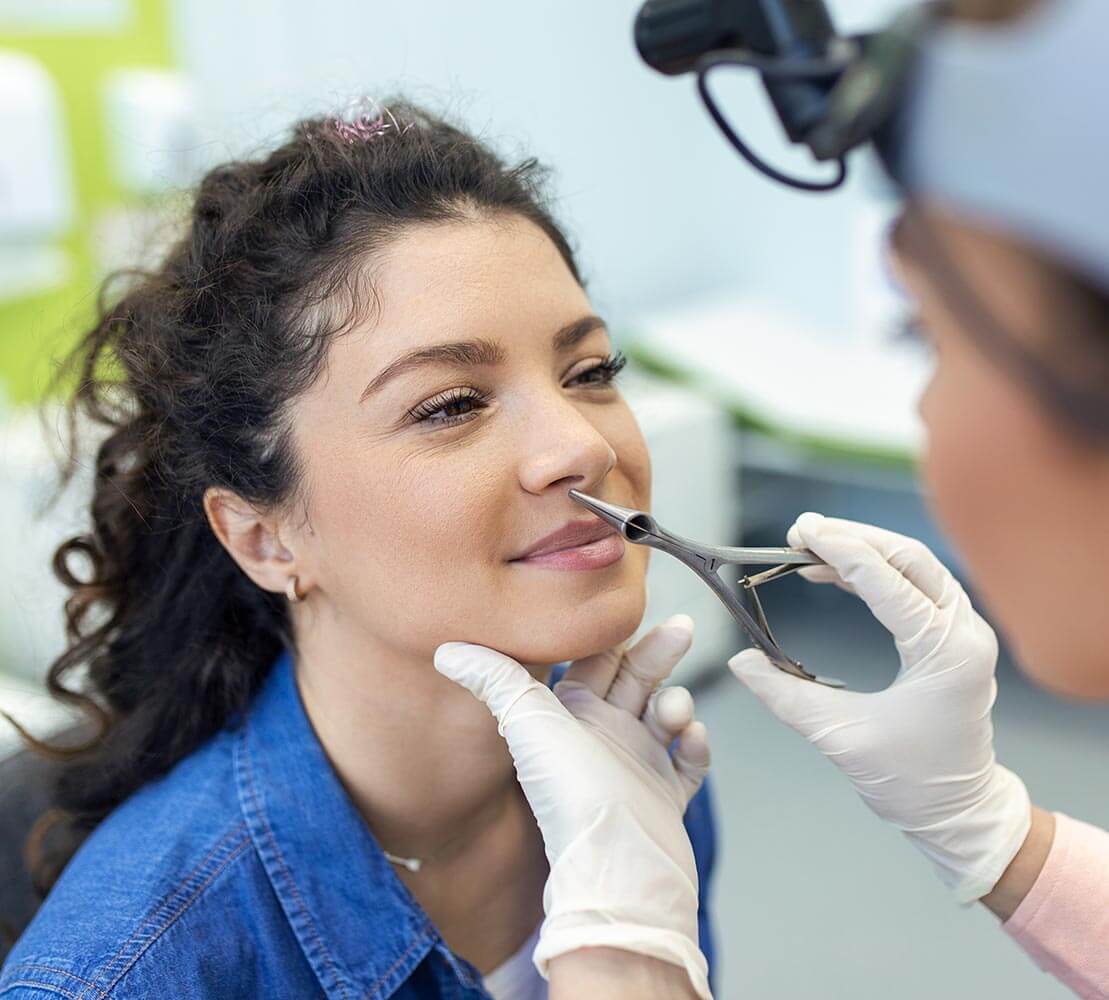 Young female patient having nose examined by ENT doctor