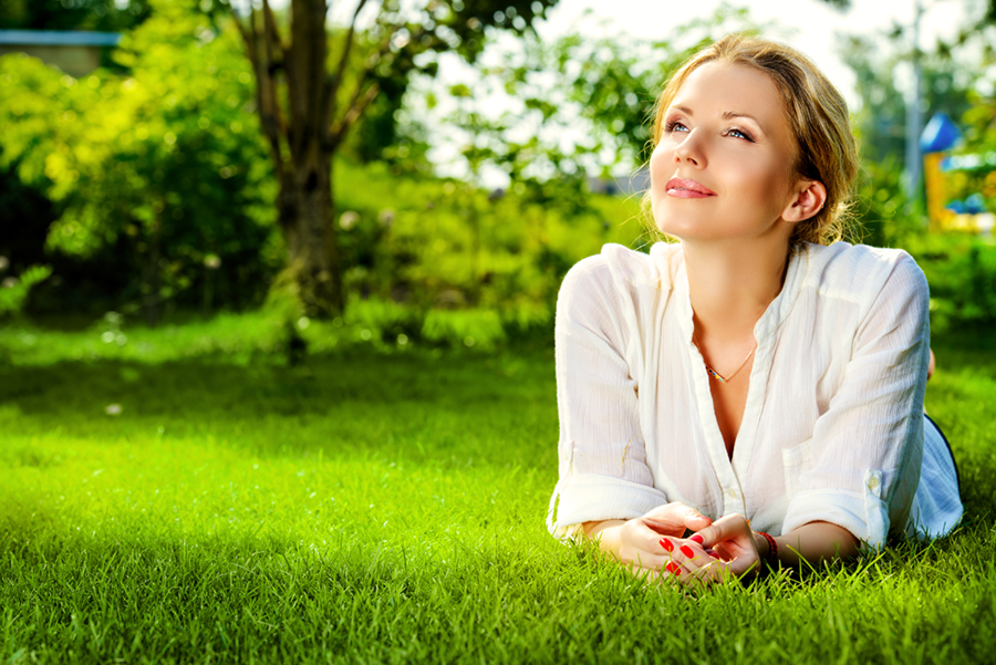 Beautiful smiling woman lying on a grass outdoor.