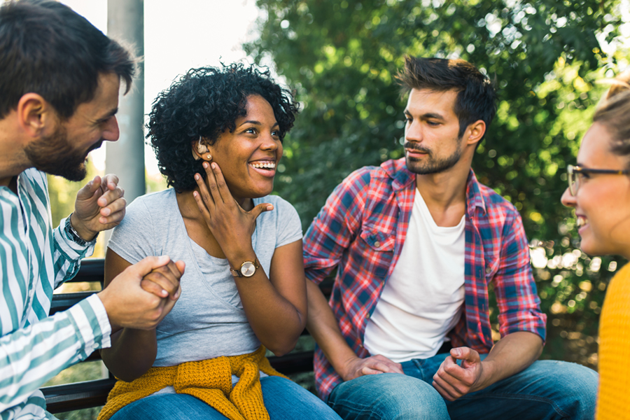 Woman with ear hearing problem having fun with her friends in the park